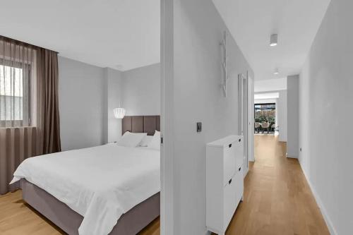 Apartmani Vila Jelena 1 في ماكارسكا: غرفة نوم بيضاء مع سرير وممر