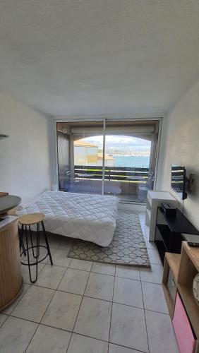 une chambre avec un lit et une grande fenêtre dans l'établissement Studio 31 Le Cap d'Agde vue mer, proche plage, l'île des pêcheurs, au Cap d'Agde