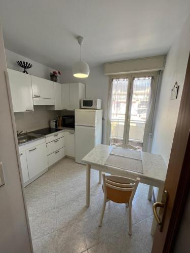 kuchnia z białymi szafkami i stołem z krzesłem w obiekcie Studio 28 m2 au calme à Menton w Mentonie