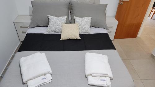 1 cama grande con 2 almohadas y toallas. en departamento de dos dormitorios en Córdoba