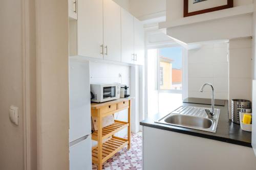 a white kitchen with a sink and a microwave at BeHappy Apartments in Lisbon