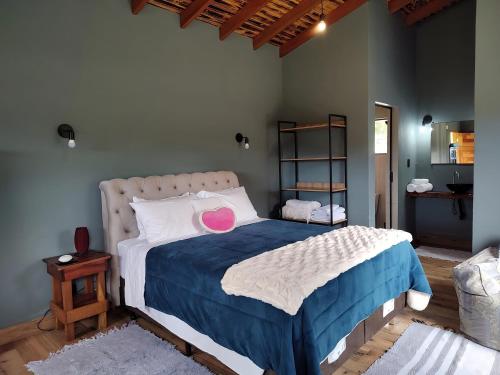 a bedroom with a bed with a pink pillow on it at Chalé Morro Grande in Paraisópolis