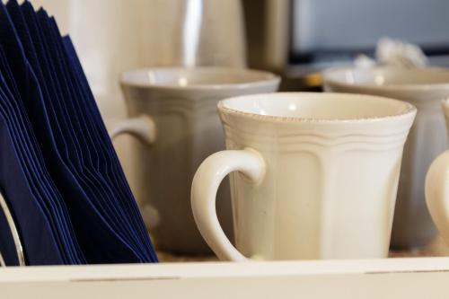 a white cup sitting on a shelf with other ceramics at Juliette Rooms in Iesi