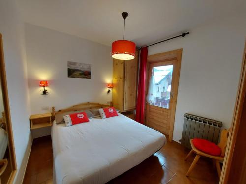 um quarto com uma cama branca e uma cadeira vermelha em BAITA SOLDANELLA - Livigno em Livigno