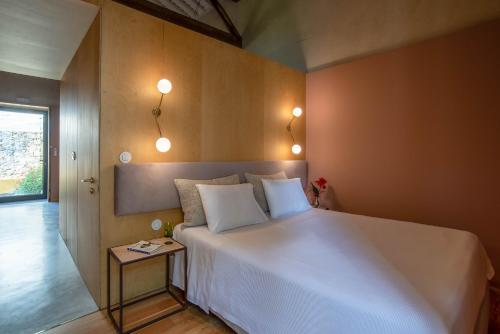 um quarto com uma grande cama branca e uma mesa lateral. em Green&Houses em Ponta Delgada