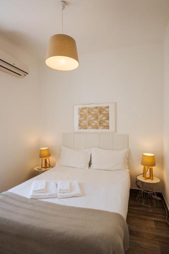a bedroom with a large white bed with two lamps at BeHappy Apartments in Lisbon
