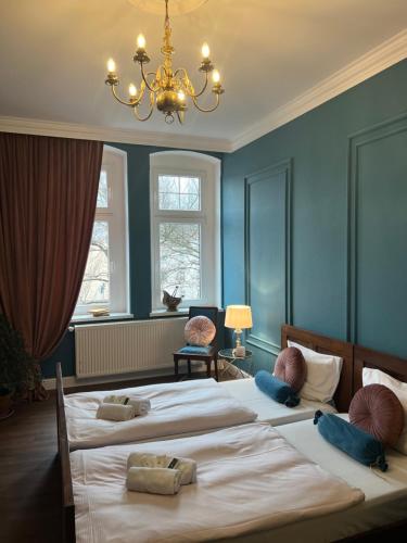 2 bedden in een slaapkamer met blauwe muren en een kroonluchter bij Apartament Baron ***** in Jelenia Góra