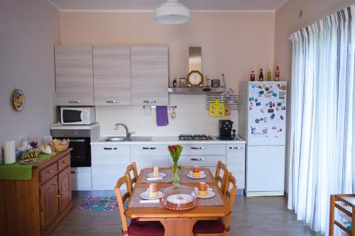 a kitchen with a table and a white refrigerator at Peppe's house in Gravina di Catania