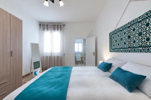 a bedroom with a large white bed with blue pillows at Appartamento Dada in Carmiano