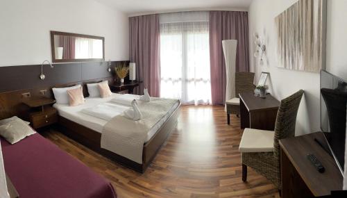 a bedroom with a large bed and a living room at Hotel Garni "Kärnten Inn" mit direktem Seezugang und E-Ladestation in Bodensdorf