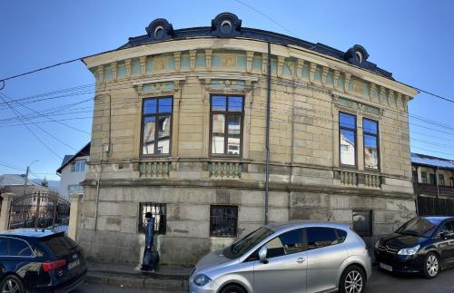 a stone building with cars parked in front of it at Casa Continentelor in Cîmpulung