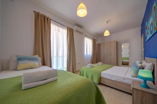 - une chambre avec 2 lits avec des draps verts dans l'établissement 2 Bedroom Apts and Penthouse close to Bugibba Promenade by ShortletsMalta, à San Pawl il-Baħar