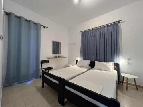 sypialnia z 2 łóżkami i niebieską zasłoną w obiekcie PebBle Apartments w mieście Marathias