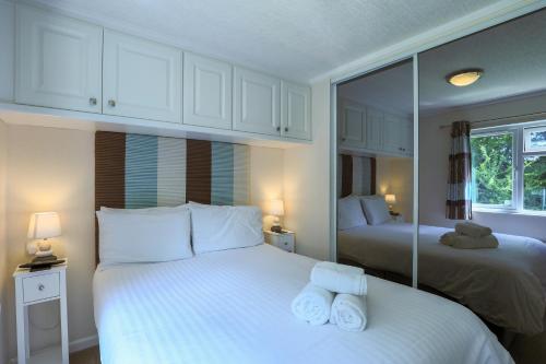 a bedroom with two beds and a mirror at Conkers Retreat at Finlake Resort & Spa, Devon in Chudleigh