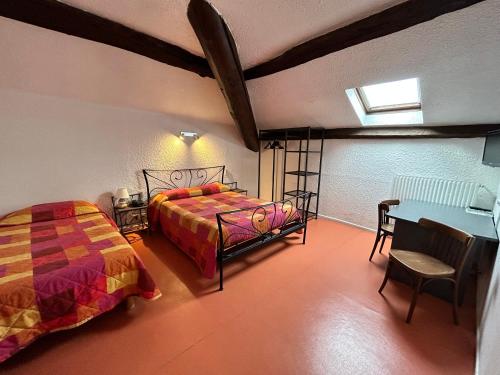 a bedroom with two beds and a desk and a table at Cit'Hotel du Tigre in Verdun-sur-Meuse