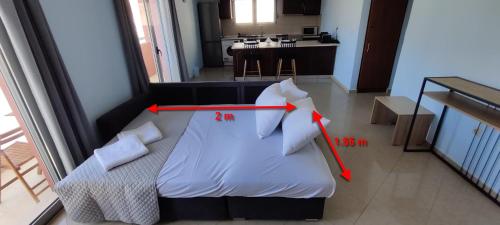um quarto com uma cama branca e duas flechas vermelhas em el greco apartment in Ilha de Rhodes