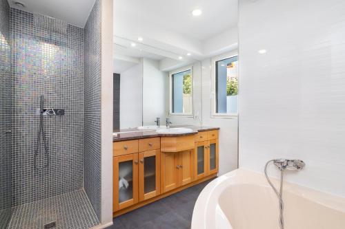 een badkamer met een bad, een wastafel en een douche bij WHome Hideaway Luxury Family Villa w/ S-Pool & AC in Ourém