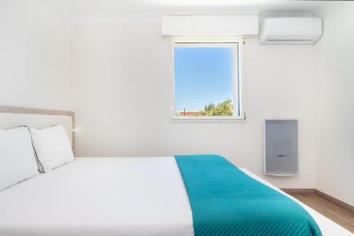 een witte slaapkamer met een bed en een raam bij WHome Hideaway Luxury Family Villa w/ S-Pool & AC in Ourém