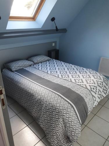 1 cama en un dormitorio con una pared azul y una ventana en Gites Des Petits Près, en Fatouville-Grestain