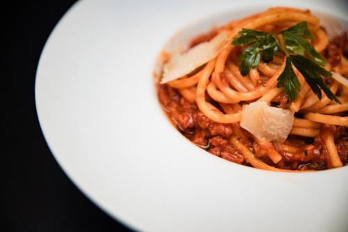 a white plate with a bowl of spaghetti and sauce at Casa Del Sole in Alba Iulia