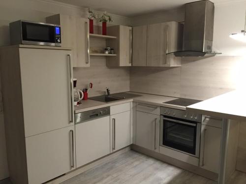 a kitchen with white cabinets and a sink and a refrigerator at Ferienwohnung am Europapark - klimatisiert in Rust