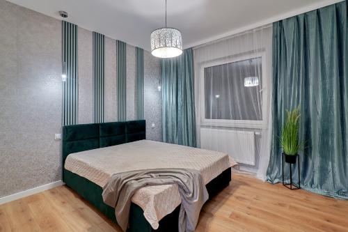 皮拉的住宿－Apartament z ogrodem，一间卧室配有一张带绿色窗帘的床和窗户。