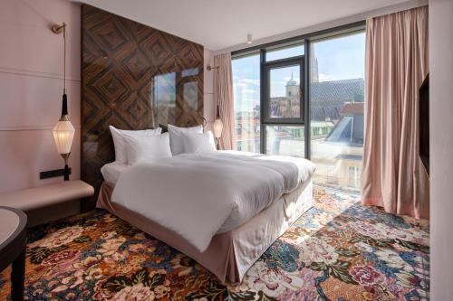 a bedroom with a large bed and a large window at Hotel Topazz & Lamée in Vienna