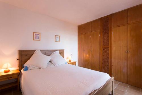 a bedroom with a large white bed and wooden cabinets at Chalet Sa Rapita in Sa Ràpita
