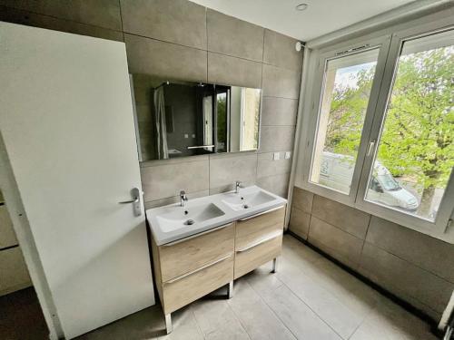 une salle de bain avec un lavabo, un miroir et une fenêtre dans l'établissement Le triangle d'or Paris-CDG- Disney, à Vaires-sur-Marne