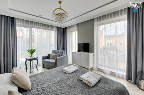 a bedroom with a bed and a chair and windows at MS Apartments Rest 5.0 in Sopot