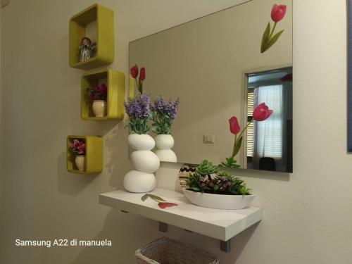 a room with a shelf with vases and flowers on it at GAIA Accommodation in Alghero