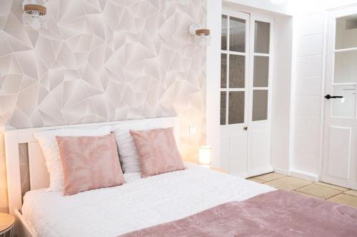 1 dormitorio con cama blanca y almohadas rosas en Appartement rénové - wifi - jardin - centre de Niort, en Niort