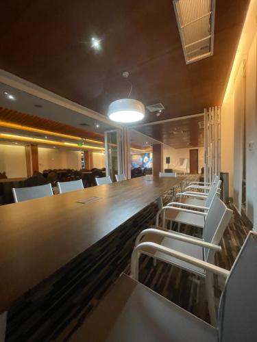 a bar with white chairs and a long table at Empyrean Dhaka City Centre in Dhaka