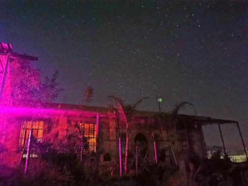 ein Gebäude mit rosa Lichtern in der Nacht davor in der Unterkunft Casa de campo con alberca in San Juan de los Lagos