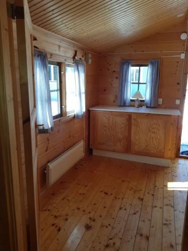 y vistas al interior de una cabaña con suelo y ventanas de madera. en Schöne Stuga unmittelbar am Ammerån gelegen, en Hammarstrand