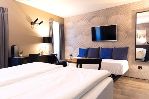 Habitación de hotel con 2 camas y TV en la pared en San Carlo Suite, en Lugano