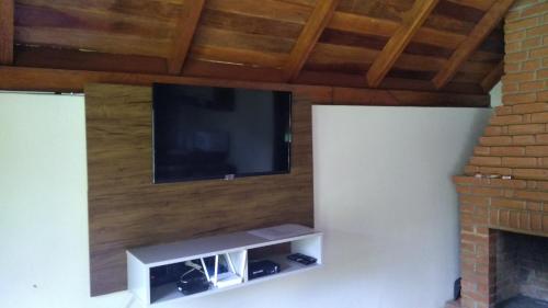 einen Flachbild-TV an der Wand mit einem Kamin in der Unterkunft Chalé Portal Lazer in Gonçalves