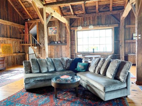 a living room with a leather couch and a table at Historic Renovated Barn at Boorn Brook Farm - Manchester Vermont in Manchester Center