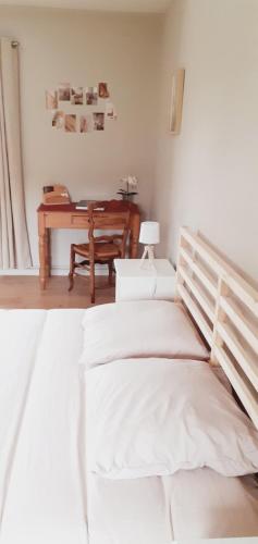 a white bedroom with a bed and a desk at Les 3 Mésanges in Giverny