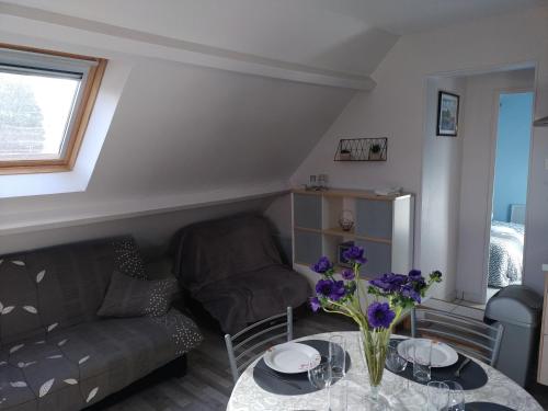 un salon avec un canapé et une table avec des fleurs dans l'établissement Gites Des Petits Près, à Fatouville-Grestain