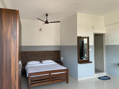 Schlafzimmer mit einem Bett und einem Spiegel in der Unterkunft SERENITY GREENS in Madikeri