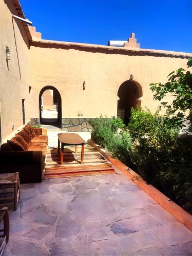 a patio with a bench and a table in front of a building at La perle de saghro in Nkob