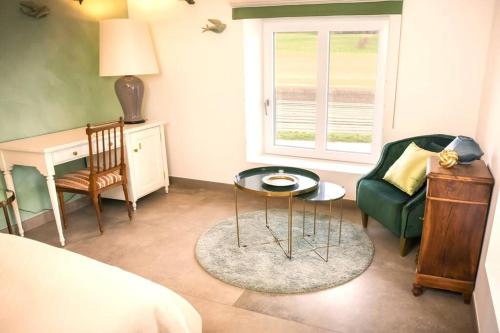 a bedroom with a couch and a table and a chair at Les Champs du Levant in Cudrefin