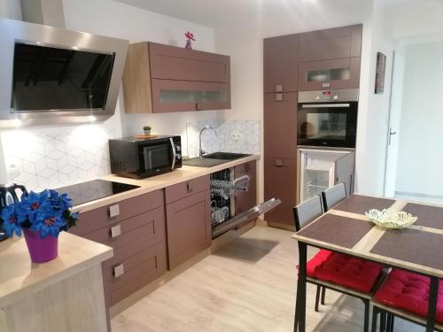 a kitchen with brown cabinets and a table and a microwave at Gîte de rarounette au cœur des Vosges in Celles-sur-Plaine