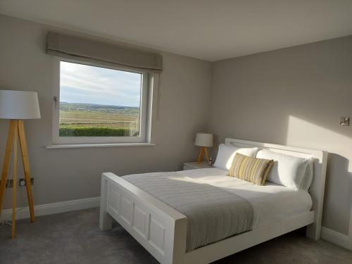a white bedroom with a bed and a window at Sunny Hill View in Lahinch