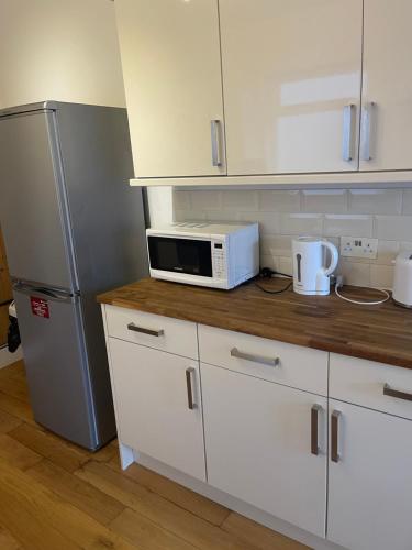 eine Küche mit weißen Schränken, einer Mikrowelle und einem Kühlschrank in der Unterkunft Small room in Horfield 3 in Bristol