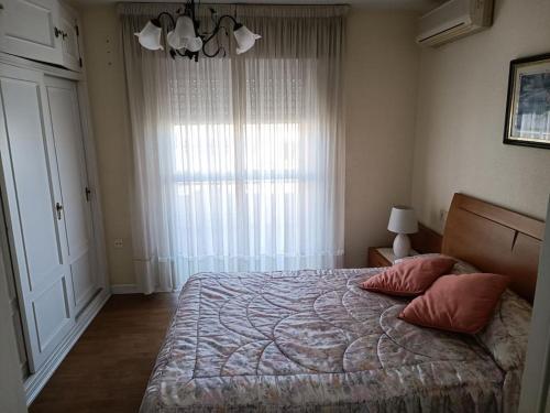 1 dormitorio con 1 cama con 2 almohadas y ventana en Gran vivienda unifamiliar céntrica y cercana al mar, en Aguadulce