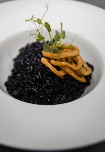 a white bowl of food with black rice and a plant at Casa Del Sole in Alba Iulia
