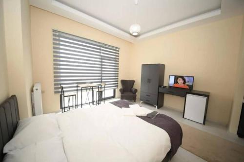 a bedroom with a large white bed and a television at Ankara Yenimahalle'de temiz ve konforlu özel oda in Yenimahalle