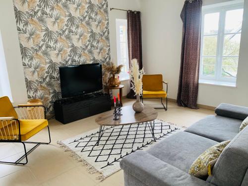 ein Wohnzimmer mit einem Sofa und einem TV in der Unterkunft La roseraie de L arguenon, spacieux appartement centre ville in Jugon Les Lacs